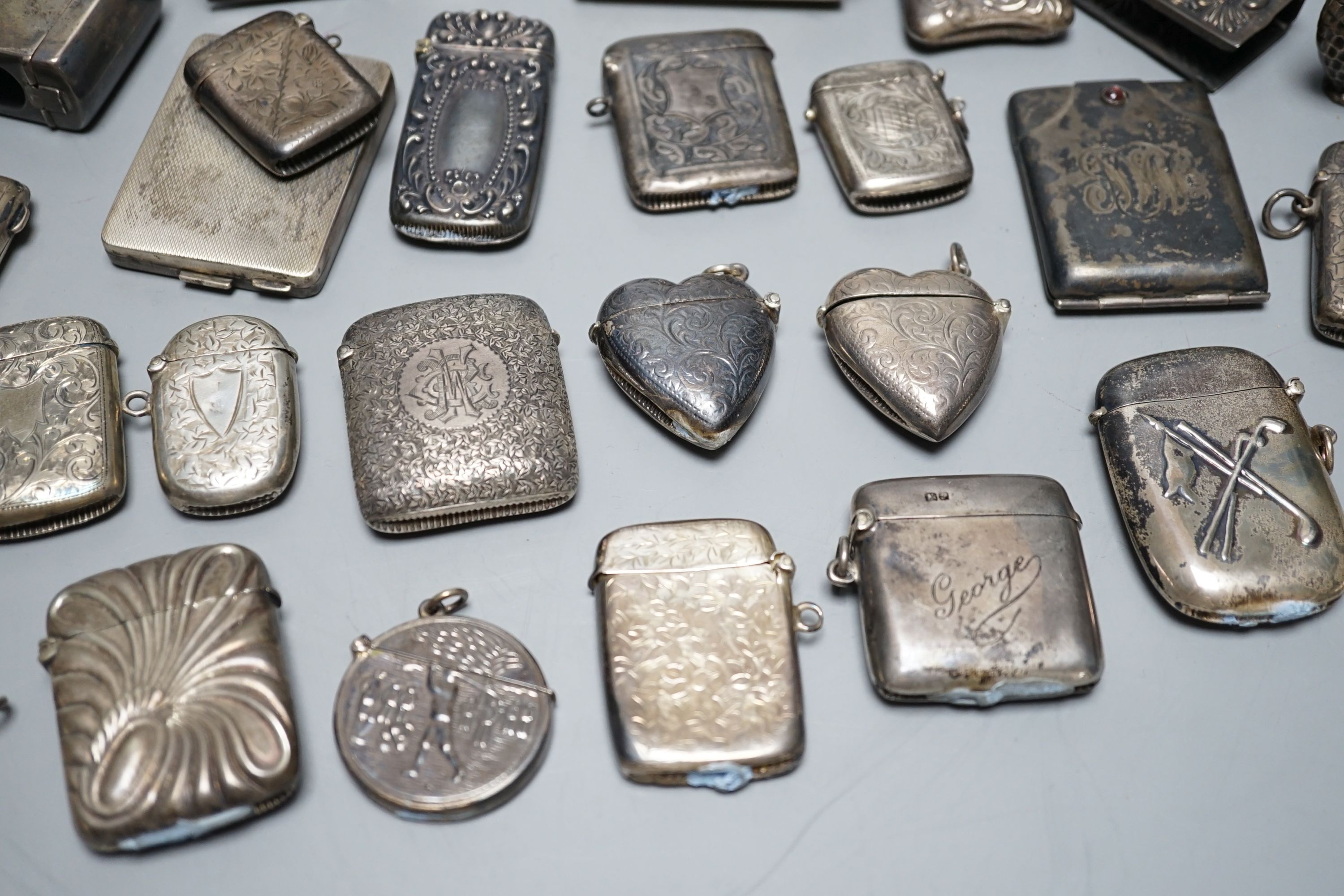 A collection of twenty six assorted mainly early 20th century silver or white metal vesta cases, including heart shape and combination vesta and cheroot cutter, largest 61mm and and seven assorted match cases or sleeves.